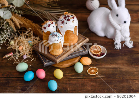 Easter eggs with cake on a brown wooden table Easter eggs with cake on a brown wooden table 86201004