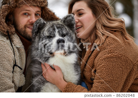 Portrait of a young beautiful couple of European appearance with a husky dog in the winter forest 86202048