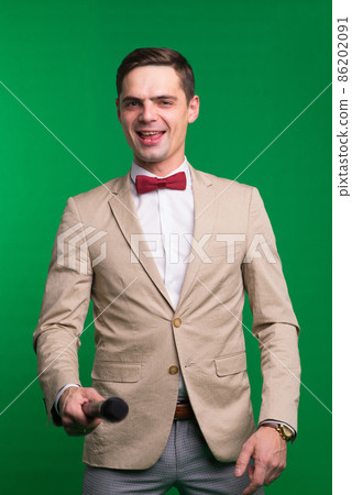 Portrait of professional male reporter holding a microphone, isolated on white and green background 86202091
