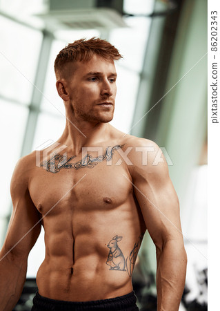 Portrait handsome and confident young Caucasian man at gym background. Face of brutal muscular sexy male. He's sweating after fitness workout. healthy and lifestyle athletic people. copy space 86202343