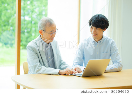 Senior man and young man looking at a computer Senior man and young man looking at a computer 86204650