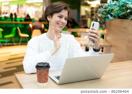 Young beautiful pretty brunette woman wearing white sweatshirt sitting at a shopping center at a Young beautiful pretty brunette woman wearing white sweatshirt sitting at a shopping center at a 86206404