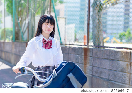A high school girl who pushes a bicycle with a smile and goes to school in a residential area. A high school girl who pushes a bicycle with a smile and goes to school in a residential area. 86206647