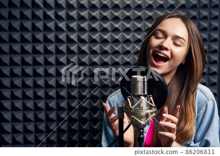 Teen girl in recording studio with mic over acoustic absorber panel background 86206811