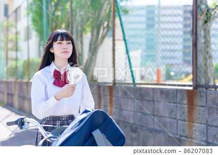 A high school girl who goes to school by pushing a bicycle while using a portable electric fan A high school girl who goes to school by pushing a bicycle while using a portable electric fan 86207083