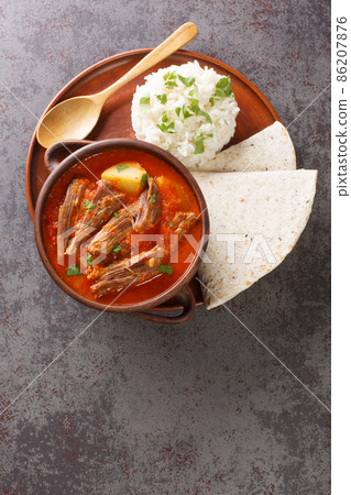 Guatemalan Shredded Beef Stew served with rice and tortilla close-up in a plate. Vertical top view Guatemalan Shredded Beef Stew served with rice and tortilla close-up in a plate. Vertical top view 86207876