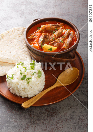 Hilachas is a traditional Guatemalan stew featuring shredded beef simmered in a lightly-spiced tomato sauce with tender potatoes closeup in the plate. Vertical 86207881