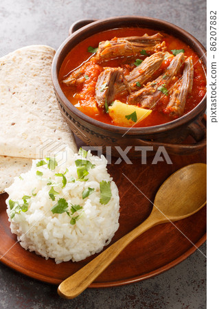 Hilachas is a Guatemalan dish consists of boiled, shredded beef served with tomato sauce and tomatillo, potatoes, carrots and Guajillo chiles closeup in the plate. Vertical 86207882