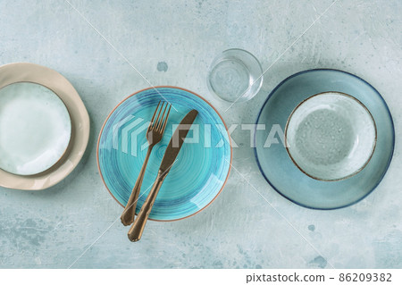 Modern dinnerware with cutlery. A vibrant blue plate with a fork and a knife 86209382