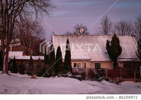 House with firs and fence in pinkish blue sunset in winter House with firs and fence in pinkish blue sunset in winter 86209972
