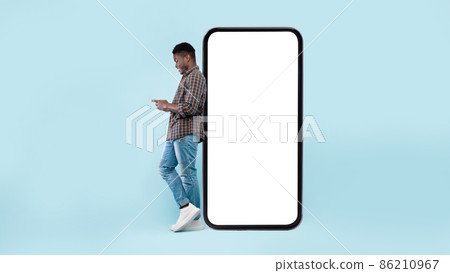 Black man leaning on white blank smartphone screen, using cellphone 86210967
