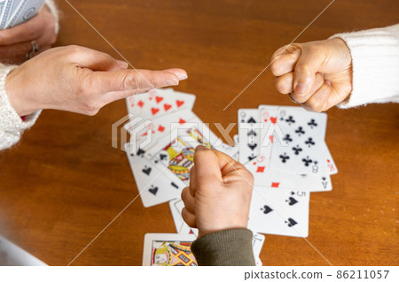 Senior woman playing rock-paper-scissors to decide the order of playing cards 86211057