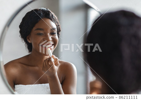 Happy african american woman applying hygienic lip balm 86211111