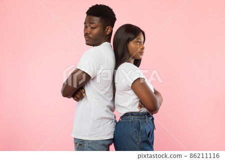 Black couple standing back to back, pink studio wall Black couple standing back to back, pink studio wall 86211116