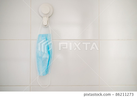 Used protective face mask hanging over the door knob. Used protective face mask hanging over the door knob. 86211273