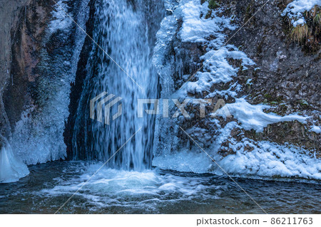 Snowy winter landscape with waterfall on a wild stream. 86211763