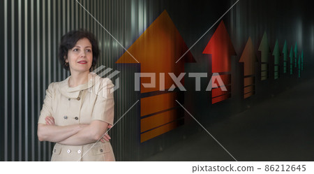 Pretty middle aged business woman in business suit, successful confidence close up head and shoulders portrait against dark wall with up arrows in perspective. Pretty middle aged business woman in business suit, successful confidence close up head and shoulders portrait against dark wall with up arrows in perspective. 86212645
