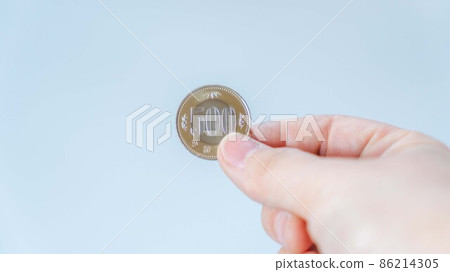 手拿著新的 500 日元硬幣 86214305