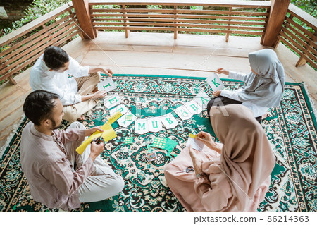 Father, mother and children make flag chain paper decorations together Father, mother and children make flag chain paper decorations together 86214363