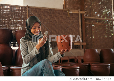 girl in hijab using mobile phone camera to photograph pottery girl in hijab using mobile phone camera to photograph pottery 86214847