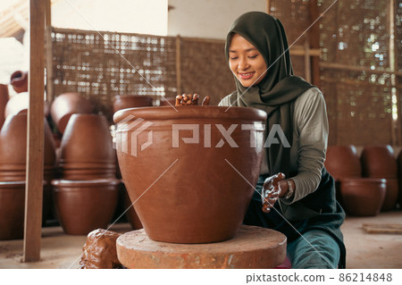 woman in hijab shapes clay into pottery on wheels woman in hijab shapes clay into pottery on wheels 86214848