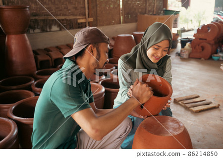 Man and girl in hijab holding pottery while chatting Man and girl in hijab holding pottery while chatting 86214850