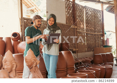 Man and woman in veil using tablet at pottery stall Man and woman in veil using tablet at pottery stall 86214899