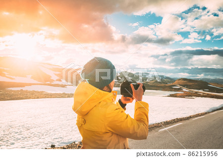 Aurlandsfjellet, Norway. Young Happy Woman Tourist Traveler Photographer Taking Pictures Photos Of Aurlandsfjellet Scenic Route Road. Norwegian Landmark And Popular Destination Aurlandsfjellet, Norway. Young Happy Woman Tourist Traveler Photographer Taking Pictures Photos Of Aurlandsfjellet Scenic Route Road. Norwegian Landmark And Popular Destination 86215956