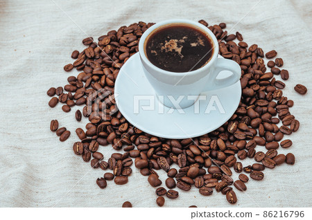 Cup of coffee and coffee beans on beige background Cup of coffee and coffee beans on beige background 86216796