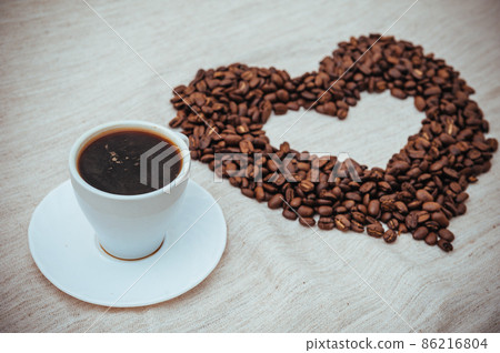 Cup of Coffe. Coffee beans in shape of heart. coffee beans isolated on white background. roasted coffee beans, can be used as a background. Cup of Coffe. Coffee beans in shape of heart. coffee beans isolated on white background. roasted coffee beans, can be used as a background. 86216804
