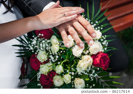 Wedding rings on the hands of the newlyweds at a wedding bouquet 86217614