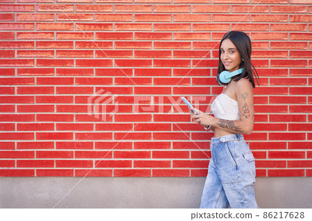 young girl goes for a walk with her headphones and smartphone young girl goes for a walk with her headphones and smartphone 86217628