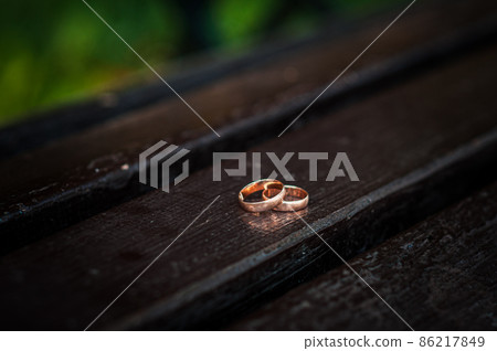 Wedding rings on a wooden stand against the background of the bride's bouquet 86217849