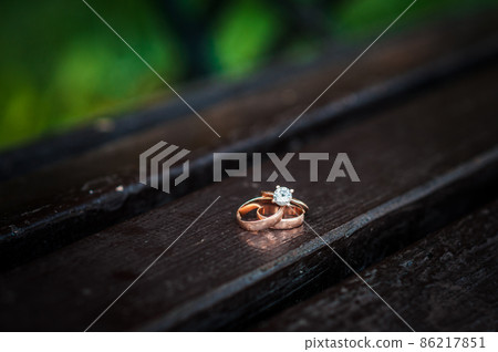 Wedding rings on a wooden stand against the background of the bride's bouquet 86217851