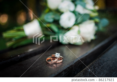 Wedding rings on a wooden stand against the background of the bride's bouquet 86217921
