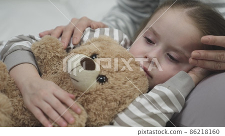 Tired girl falls asleep on mother laps hugging teddy bear 86218160