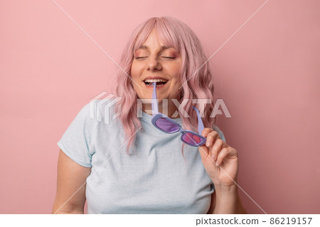 Happy cheerful young 30s woman blogger with stylish glasses posing isolated over pink studio background. Happy cheerful young 30s woman blogger with stylish glasses posing isolated over pink studio background. 86219157