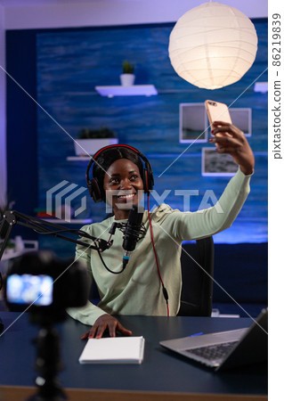 Woman influencer with headphones holding smartphone taking photo Woman influencer with headphones holding smartphone taking photo 86219839