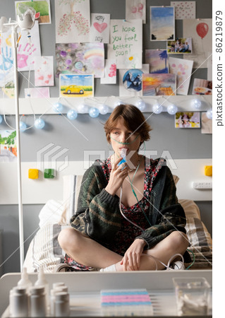 Sick teenage girl with oxygen nose pipe breathing through mouth with inhaler 86219879
