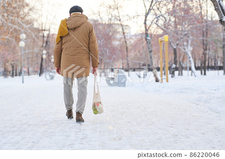 Rear view of old man in casualwear going back home after supermarket 86220046