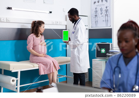 Pregnant woman looking at vertical green screen on tablet 86220089