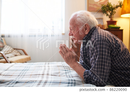 Old religious man with his hands put together in front of face 86220090