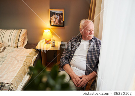 Serene and relaxed senior man sitting in armchair by window Serene and relaxed senior man sitting in armchair by window 86220102