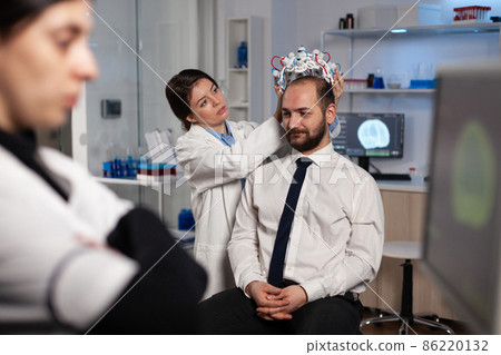 Specialist neurologist woman adjusting eeg headset analyzing brain activity of man patient 86220132
