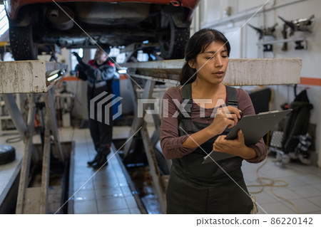 Young pretty female worker of car service making notes Young pretty female worker of car service making notes 86220142