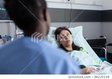 Over shoulder view of patient with nasal cannula recieving oxygen recovering on hospital bed 86220149