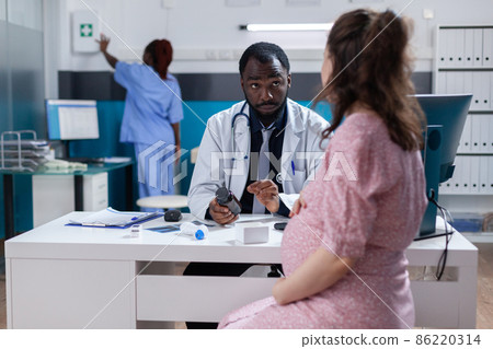 African american doctor giving bottle of pills to pregnant woman African american doctor giving bottle of pills to pregnant woman 86220314