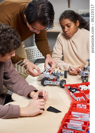 Man teaching children to build the robot 86220317
