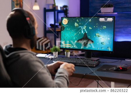 Man playing video games with controller and headphones 86220322