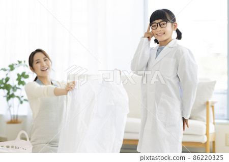 A girl in a lab coat and a housewife folding laundry A girl in a lab coat and a housewife folding laundry 86220325